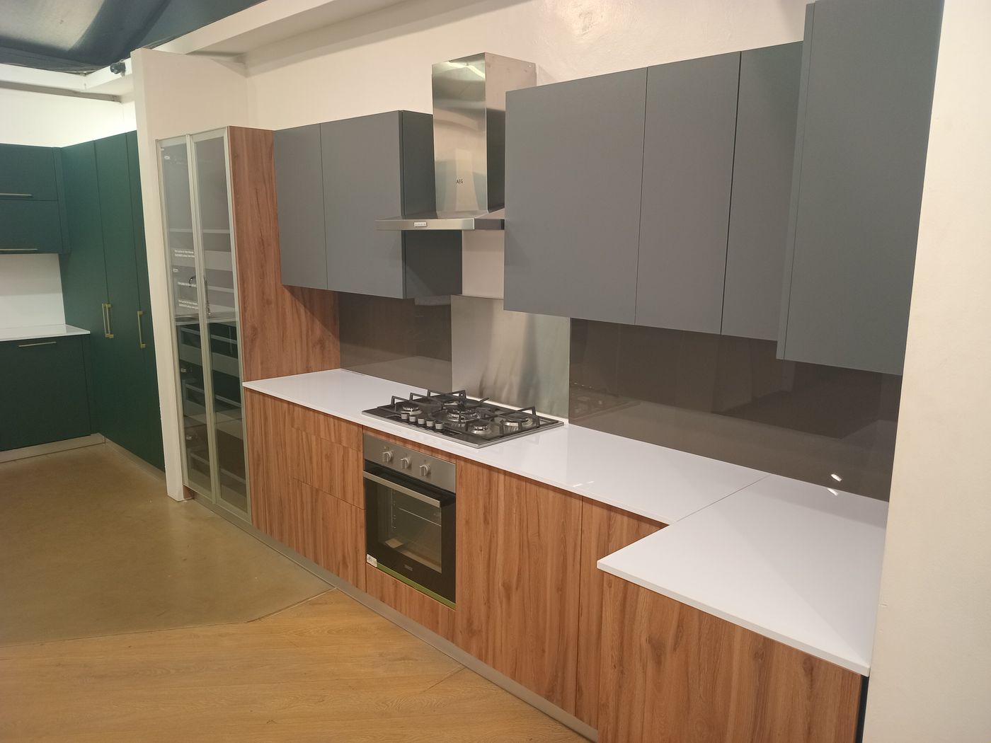 Modern fitted kitchen with grey wall cabinets, wood-grain base units and white worktop, made by Procut